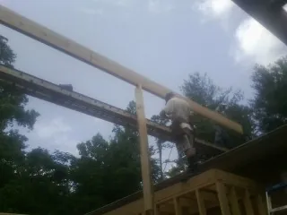 Carpenter setting a ridge beam over a new addition frame — Ice Dam Removal by Roofing Brothers in Greenview