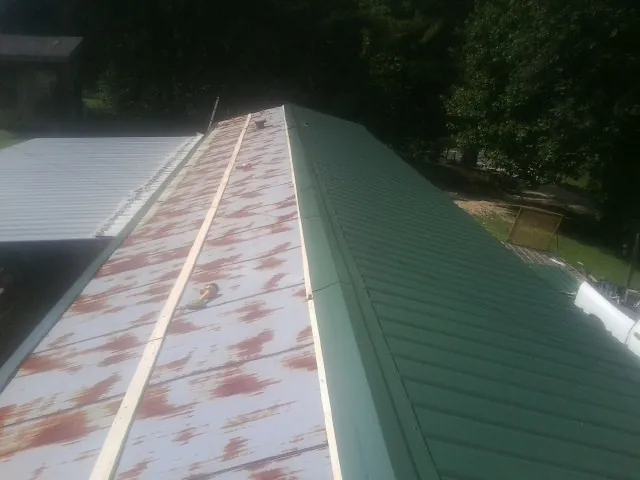 Old rusted panels beside newly installed green metal roofing — Wind Damage Roof Repair by Roofing Brothers in Greenview