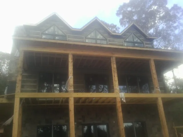 Dormers and porch framing on a large log home under construction — Roof Coating work by our crew in Greenview